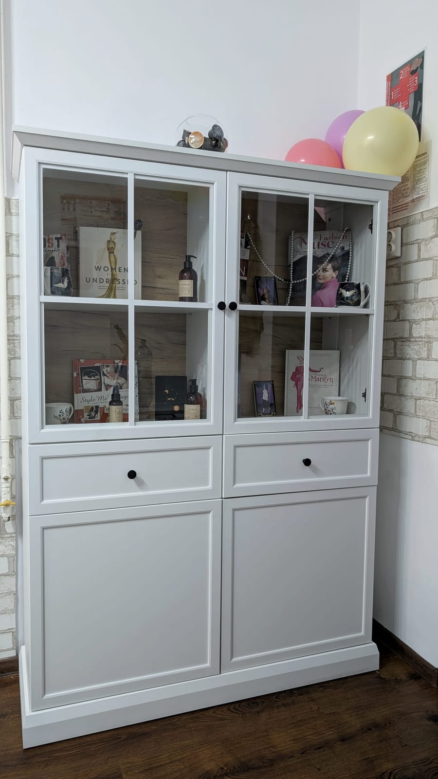 Detaliu din salon — vitrina cu cărți, produse și obiecte decorative